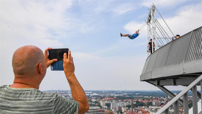 Der Bremerhavener Roland Kuhring ist der erste zahlende Gast auf der High Swing-Schaukel 86 Meter über den Havenwelten. Das muss Oliver Boek natürlich mitfilmen.
