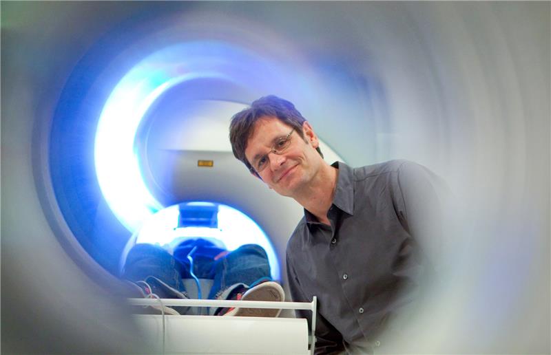 Der Direktor des Instituts für Systemische Neurowissenschaften des Universitätsklinikums Hamburg-Eppendorf (UKE), Christian Büchel, steht neben einem funktionellen Magnetresonanztomographen (fMRT), in dem ein Proband liegt. Foto: Bodo Marks/dpa