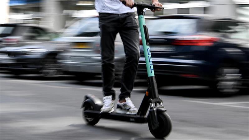 Ein Mann fährt auf einem E-Scooter.
