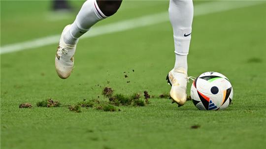 Englands Bukayo Sako dribbelt mit dem Ball auf dem ramponierten Rasen.