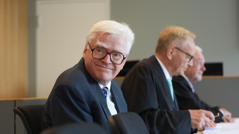 Der „Euroimmun“-Gründer Winfried Stöcker (l) sitzt neben seinen Rechtsanwälten Wolfgang Kubicki (r), FDP-Politiker und Vizepräsident des Deutschen Bundestages, sowie Manfred Parigger im Sitzungssaal im Amtsgericht zu Beginn eines Prozesses wegen eines Strafbefehls für eine Impfaktion mit einem eigenen Corona-Impfstoff im November 2021.