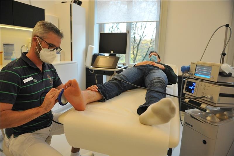 Der Facharzt Andreas Barke behandelt Dominik Axmanns Fuß mit Hilfe von Stoßwellen . Foto: Scholz
