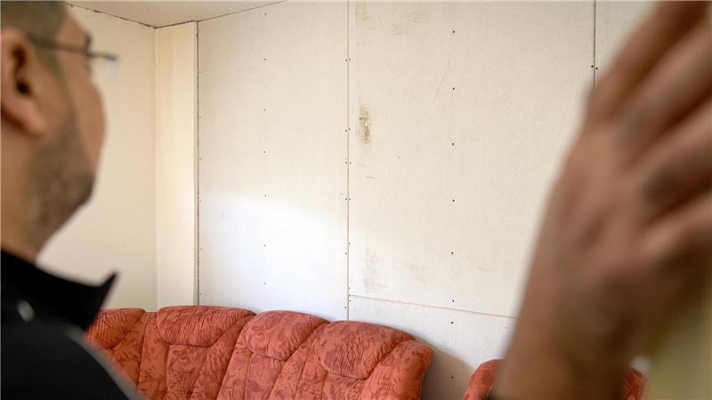 Der Familienvater blickt auf die provisorische Wand im Wohnzimmer, die erst vor wenigen Tagen notdürftig geflickt wurde. Ein seit mehreren Monaten andauernder Wasserschaden verursacht Schimmelbildung.