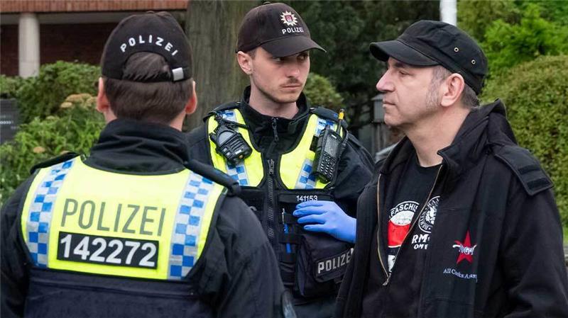 Polizei verhindert Straßenblockade der Klimaaktivisten am Hamburger Michel Der Fernsehkoch Ole Plogstedt steht bei einer Versammlungsauflösung neben Polizisten, die Personalien überprüfen. Foto: Bodo Marks/Bodo Marks/dpa