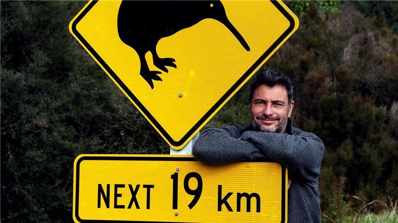 Island und Neuseeland: Roland Marske zeigt neue Multi-Visions-Shows Der Fotograf, Journalist und Weltreisender Roland Marske an einem Kiwi-Schild in Neuseeland.