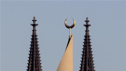 Der Halbmond auf einer Moschee ist zwischen den Türmen des Kölner Doms zu sehen. Der Auftritt eines hochrangigen afghanischen Taliban-Funktionärs in einer Kölner Moschee löst harsche Kritik aus.