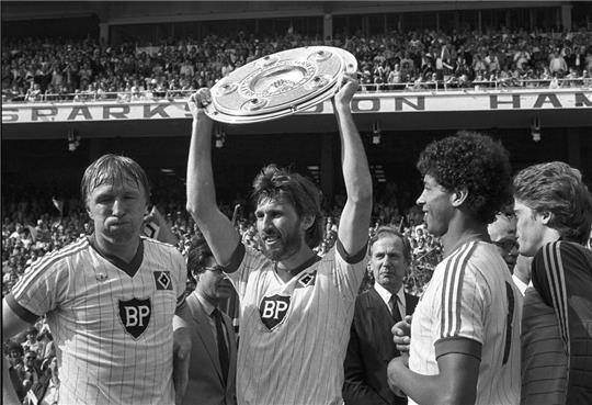 Der Hamburger SV und der Karlsruher SC trennen sich am letzten Spieltag der Saison am 29.05.1982 in Hamburg 3:3 unentschieden. Durch den Punktgewinn gewann der HSV die Deutsche Fußballmeisterschaft. Manfred Kaltz hält die Meisterschale neben Horst Hrubesch (von links), William 'Jimmy' Hartwig und Torwart Ulrich 'Uli' Stein hoch. Foto: Werner Baum/dpa