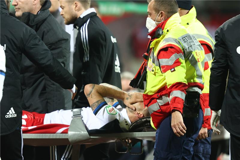 Der Hamburger Tim Leibold (M) wird verletzt vom Platz getragen und hat die Hände vors Gesicht genommen. Foto: Daniel Karmann/dpa