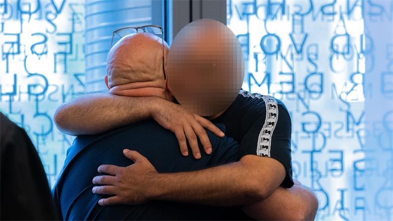 Sechseinhalb Jahre Haft nach großem Waffenfund in Remscheid Der Hauptangeklagte (links) und ein Angeklagter umarmen sich in einem Gerichtssaal im Justizzentrum. (Archivbild)