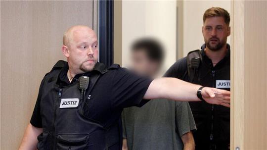 Der Hauptangeklagte wird von Justizbeamten in den Gerichtssaal geführt.