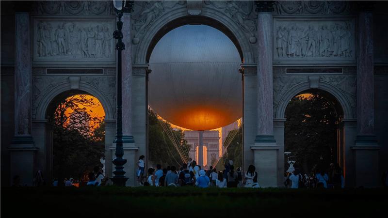 Der Heliumballon, der während der Olympischen Spiele 2024 verwendet wurde, und der Arc de Triumph sind bei Sonnenuntergang in Paris sehen.