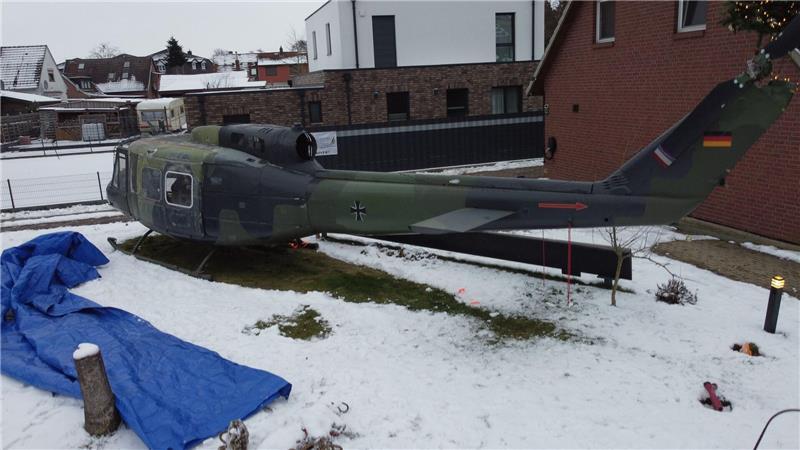 Der Hubschrauber steht mitten im Garten einer Wohnsiedlung.