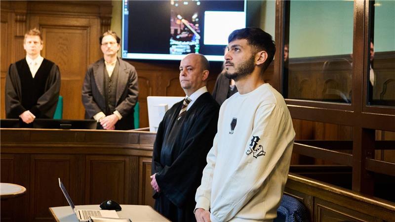 Influencer schießt Rakete in Wohnung - Bewährungsstrafe Der Influencer (r), der eine Silvesterrakete in eine Wohnung geschossen hat, steht mit gefalteten Händen im Gerichtssaal neben seinem Rechtsanwalt.