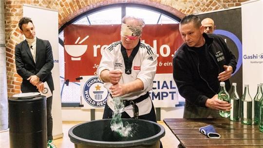 Der Kampfsportler Muhamed Kahrimanovic beim Versuch, mit verbundenen Augen und einem rohen Ei in der Hand Glasflaschen zu zerschlagen.