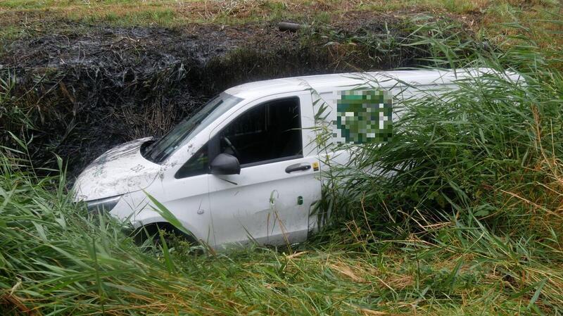 Der Kleintransporter steht im tiefen Wassergraben.