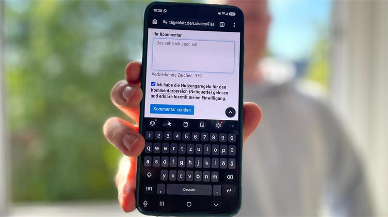 Ein Mann hält ein Smartphone in die Kamera.