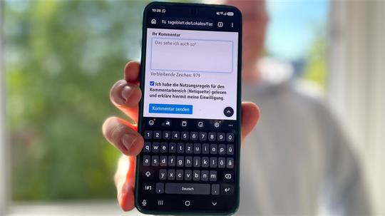 Ein Mann hält ein Smartphone in die Kamera.