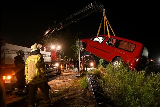 Der Kran der Kreisfeuerwehr holt den roten VW Caddy in Grünendeich am Lühe-Anleger aus dem Wasser.