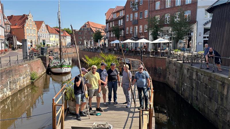 Der Kunstkudder ist heil an seinem vorübergehenden Standort angekommen: Mitglieder des Vereins Alter Hafen freuen sich zusammen mit Frank Tinnemeyer (SMTG) über die gelungene Aktion im Hafenbecken.
