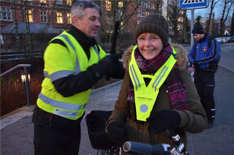 Stade: Polizei hat Fahrradfahrer im Blick Der Leiter des Verkehrsamts Gerhard Timm übergibt einen Reflektorkragen an eine Radfahrerin. Foto: Polizei