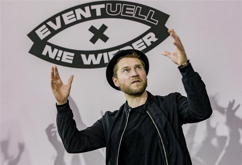 Der Musiker Johannes Oerding unter einem Logo der Kampagne „Eventuell x Nie Wieder“. Foto: Heimken/dpa