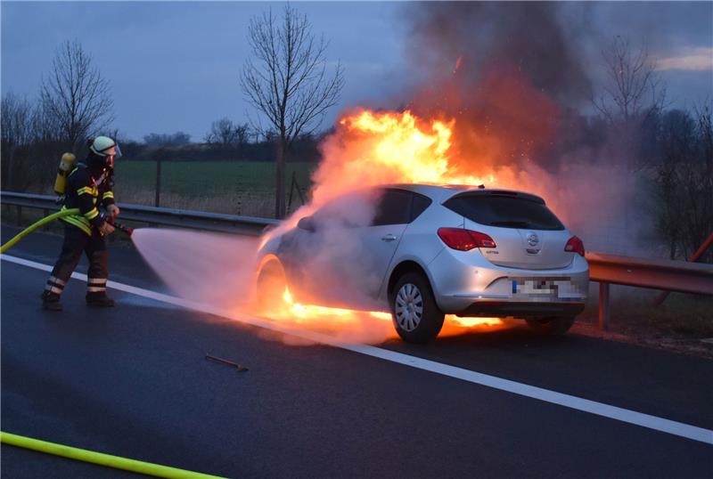 Der Opel Astra steht in Vollbrand, die Feuerwehrleute beginnen mit den Löscharbeiten. Foto: Vasel