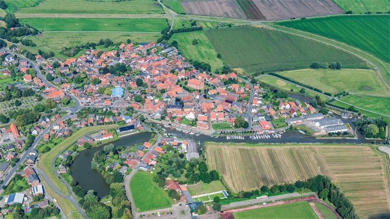 Verkehrte Welt: Deich soll zum Schutz von Freiburg abgetragen werden Der Ortskern von Freiburg. Der alte Deich schmiegt sich links unten im Bild als grünes Band an die dunkle Wasserfläche des Bassins. Oben im Bild führt der neue Ringdeich als hellgrünes Band mit Abstand um den Ort.