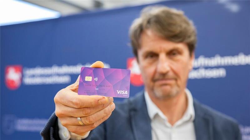 Neue Bezahlkarte an Geflüchtete verteilt Der Präsident der Landesaufnahmebehörde präsentiert eine der ersten Bezahlkarten für Geflüchtete.