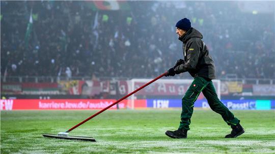 Der Rasen wird von einem Greenkeeper in der Halbzeit von Schnee befreit. Vor dem Jahres-Auftakt am Wochenende schaut die Bundesliga auf die kritische Wettersituation.