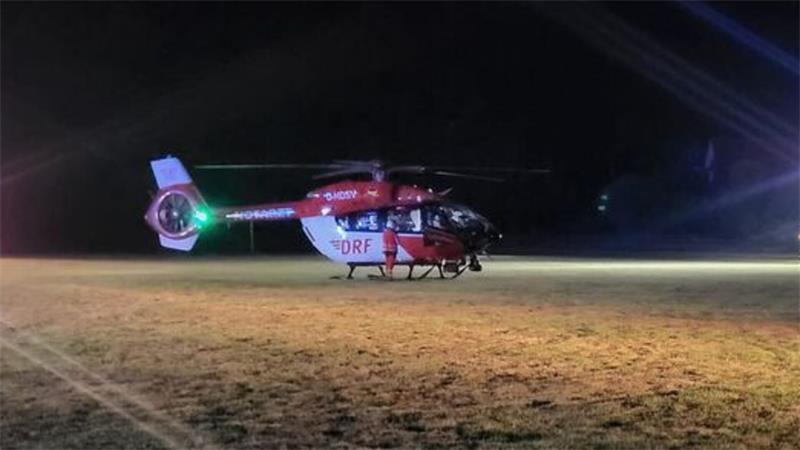 Der Rettungshubschrauber „Christoph 42“ steht auf dem Sportplatz am Heideweg. Die Feuerwehr sichert und beleuchtet den Landeplatz für den Transport.