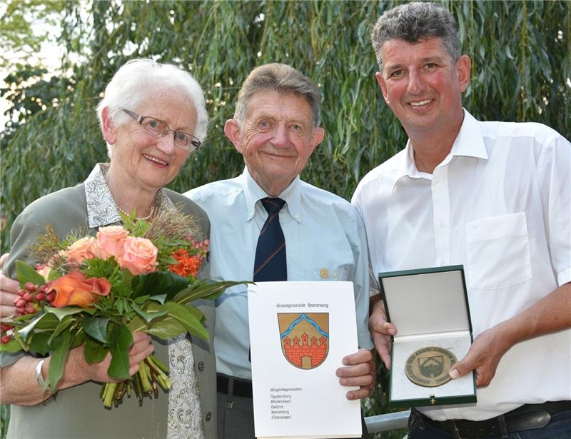 Horneburger Ehrentaler für Helmut Schering Der Samtgemeindebürgermeister Matthias Herwede (rechts) überreicht den Horneburger Ehrentaler und die Urkunde an den Heimatkundler Helmut Schering. Blumen bekommt seine Frau Helene-Marie, die bei der Feierstunde im Burgmannshof am Klavier saß. Foto: Beneke