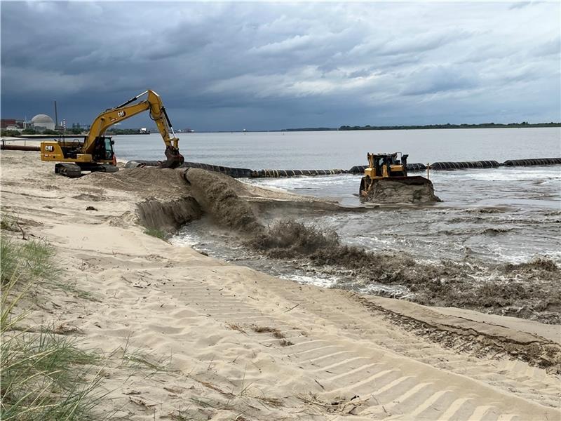 Wie die „Sandkanone“ von Bassenfleth den Strand wachsen lässt Der Sand-Wasser-Mix schießt aus der Schwimmrohrleitung auf den Strand in Bassenfleth. Der grobe Sand setzt sich ab. Satellitenunterstützt profiliert die Raupe den Strand. Fotos: Vasel