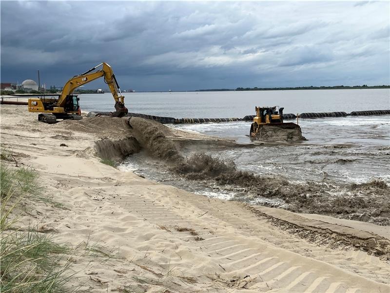 Der Sand-Wasser-Mix schießt aus der Schwimmrohrleitung auf den Strand in Bassenfleth. Der grobe Sand setzt sich ab. Satellitenunterstützt profiliert die Raupe den Strand. Fotos: Vasel