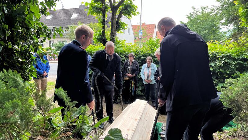Der Sarg mit den Überresten von 80 Menschen aus dem 17./18. Jahrhundert wird heruntergelassen.