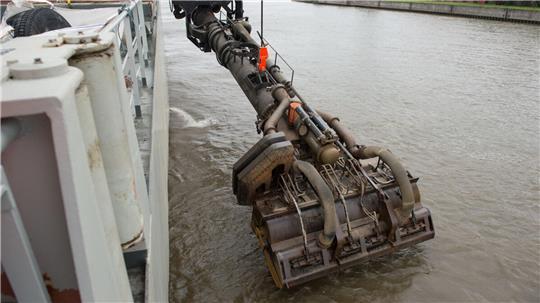 Der Saugkopf eines Baggerschiffes wird in die Elbe gesenkt. Das Spezialschiff baggert Schlick aus der Elbe in seinen Laderaum und verklappt diesen anschließend in der Nordsee.