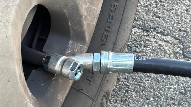 Der Schlauch des Druckluftgeräts wird auf das Ventil am Autoreifen geklemmt.