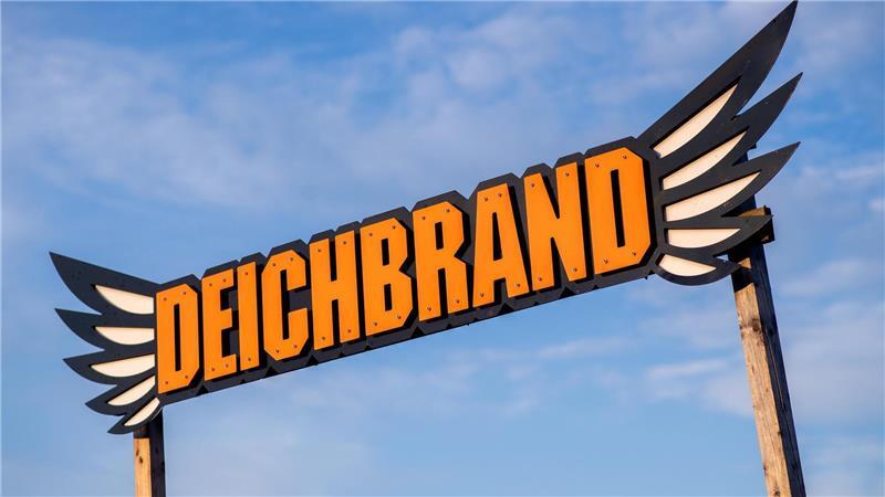 Der Schriftzug des Deichbrand-Festivals steht vor einer Bühne auf dem Festivalgelände. 