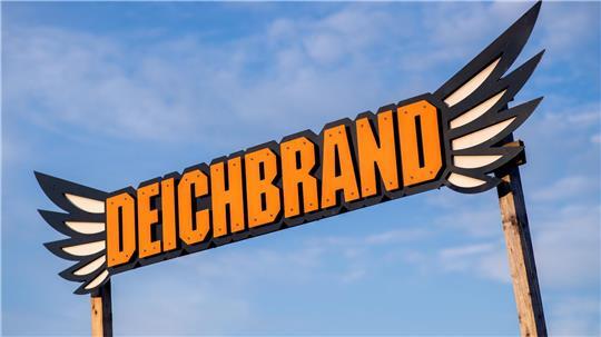 Der Schriftzug des Deichbrand-Festivals steht vor einer Bühne auf dem Festivalgelände. 