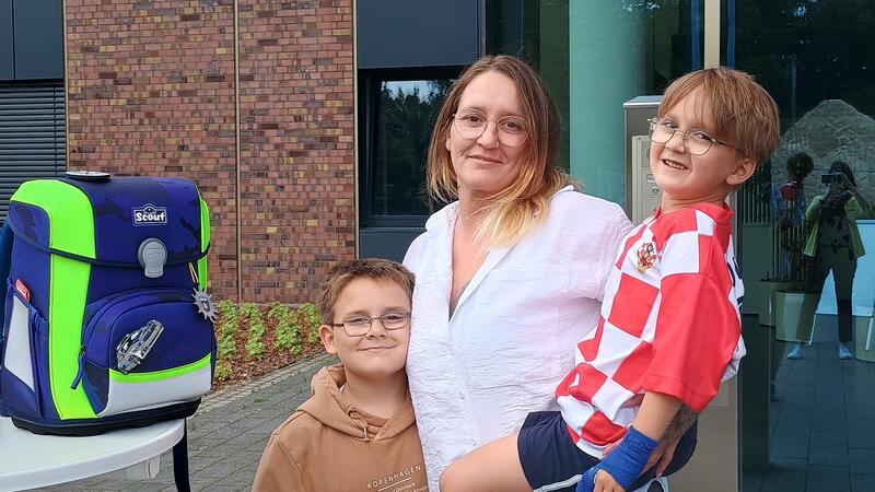 Der Schulranzen auf Blickweite und der künftige Schulanfänger Jorik auf dem Arm seiner Mutter Linda Anderson. Daneben sein Bruder Joshua, ebenfalls fröhlich dabei.