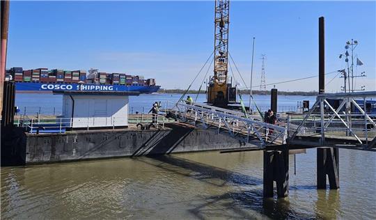 Der Schwimmkran hängt die Landungsbrücke für den Kaffeeklappe-Ponton in Twielenfleth ein.