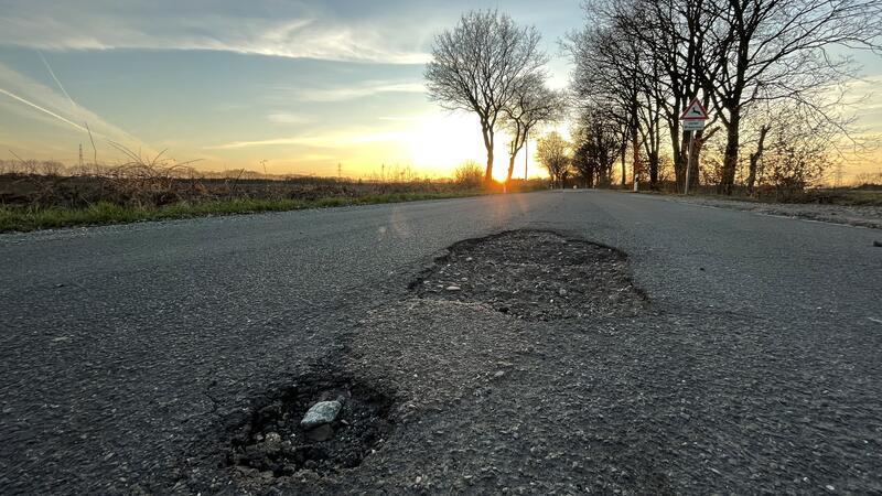 Schlaglöcher im Hagener Weg in Dollern während eines Sonnenuntergangs.