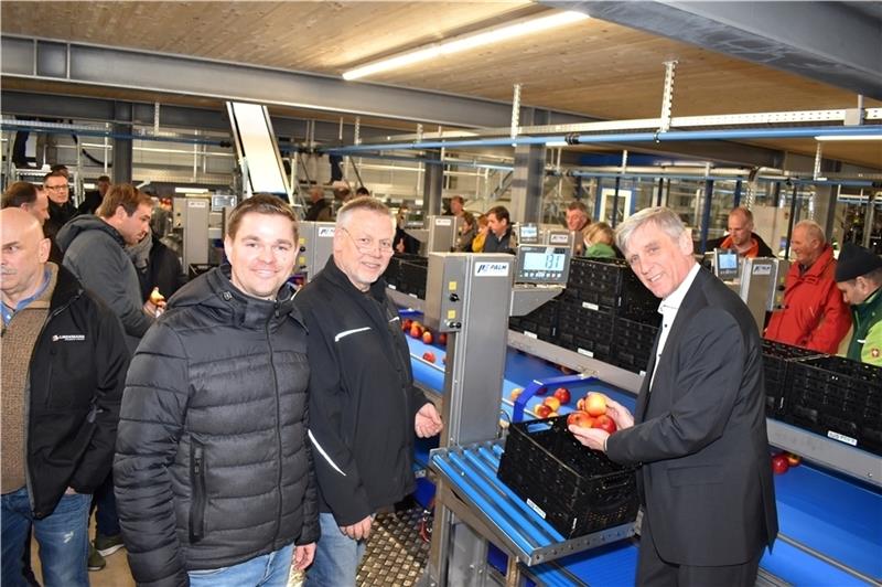 Der Staatsrat der Behörde für Wirtschaft, Verkehr und Innovation, Dr. Torsten Sevecke (SPD, rechts), packt schorfresistente Bio-Äpfel der Sorte Natyra in dem neuen Packhaus der Bio Obst Hamburg ab. Geschäftsführer Marco Bartels und Heinrich