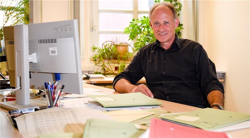 Der Statistiker Hergen Bruns sitzt an einem mit Akten vollgestellten Schreibtisch. Foto Heimken/dpa