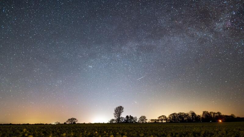 Der Sternenhimmel leuchtet über einem Rapsfeld in Schleswig-Holstein.