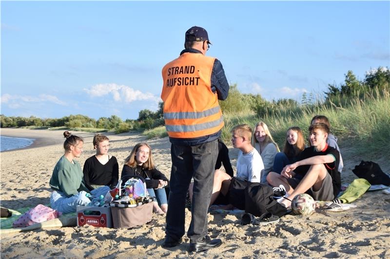 Der Strandwärter spricht mit einer Gruppe Jugendlicher, die am Freitagabend Geburtstag feiern.
