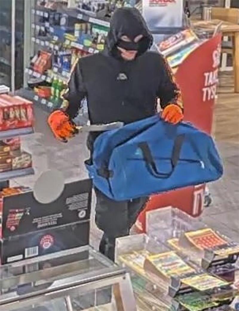 Der Täter hält ein Messer und eine blaue Tasche in der Hand.