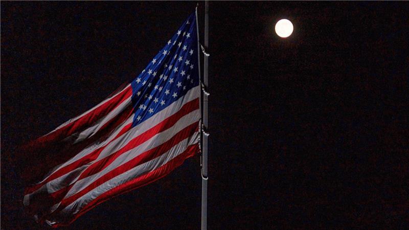 Der Vollmond geht hinter der auf Halbmast stehenden amerikanischen Flagge auf dem Südrasen des Weißen Hauses auf.