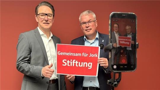 Der Vorstandsvorsitzende der Sparkasse Stade-Altes Land, Michael Senf, und der Jorker Bürgermeister Matthias Riel präsentieren das Ergebnis des Namenswettbewerbes der neuen Bürgerstiftung.