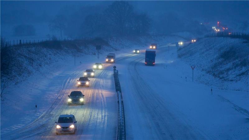 Der Winter ist zurück: Autos fahren auf einer verschneiten Straße in Fahrtrichtung Rennerod in Rheinland-Pfalz.