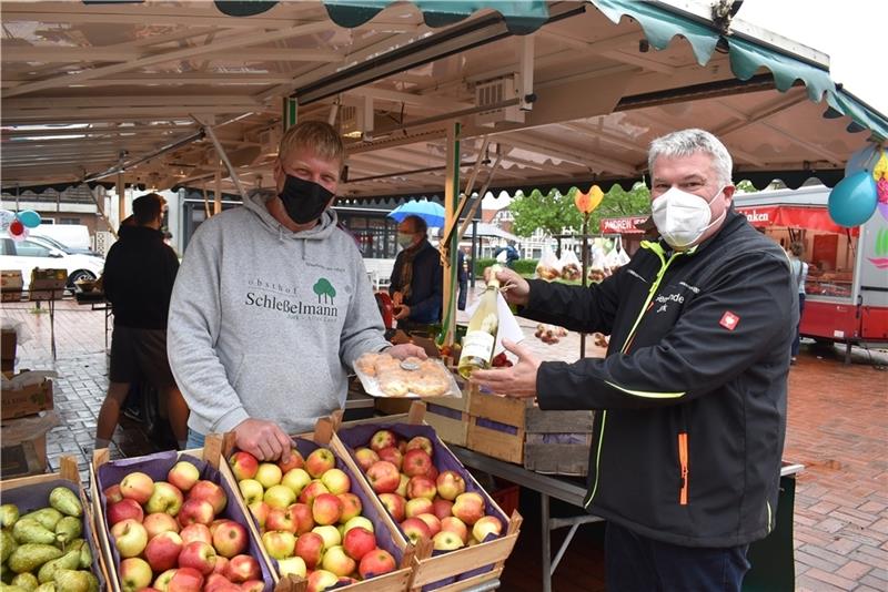 Der Wochenmarkt in Jork feiert sein zehnjähriges Jubiläum: Bürgermeister Matthias Riel überreicht Dennis Bendtsen vom Obsthof Schleßelmann das Dankeschön der Gemeinde Jork. Foto: Vasel